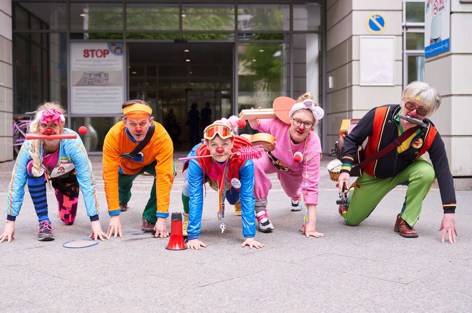 Fünf Clowns stehen in den Startlöchern für einen Staffellauf.