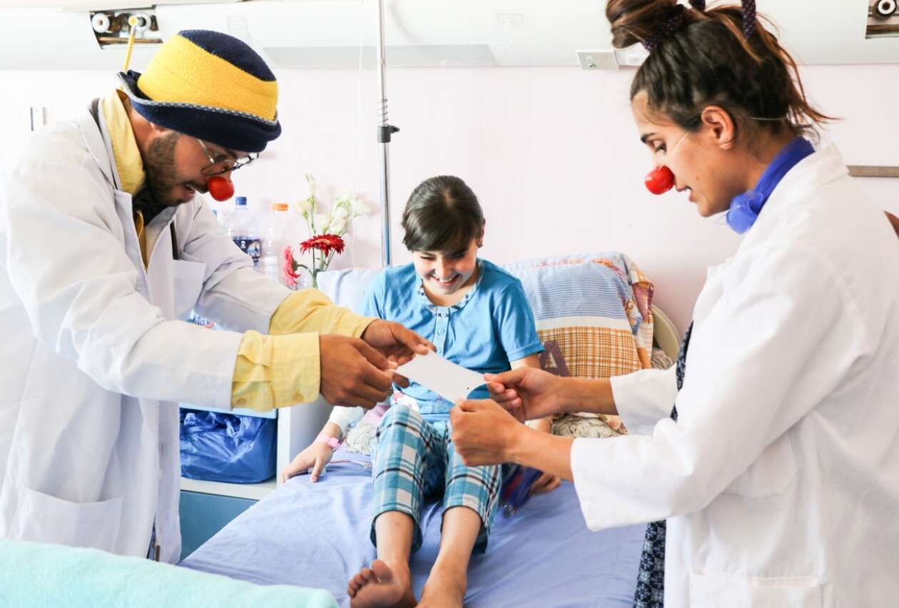 Zwei Clowns zeigen einem Kind in seinem Krankenhausbett einer ihrer Tricks 