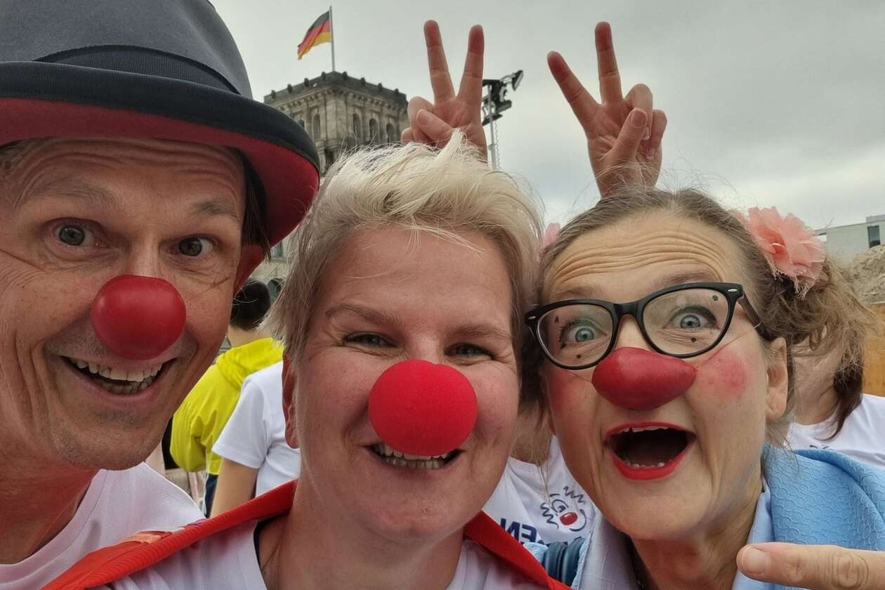 Zwei Clowns und eine Läuferin lachen in die Kamera.