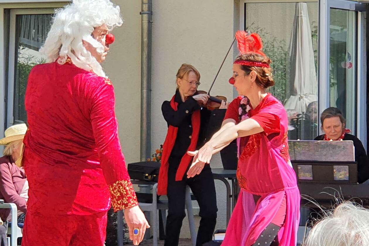 Die Schauspieler und Klinikclowns Juliane Altenburg und Leopold Altenburg tragen Verkleidungen, die an Barock und an die zwanziger Jahre erinnern. Sie tanzen auf dem Innenhof einer Pflegeeinrichtung zu Livemusik. Im Hintergrund die Pianistin Susanne Meier und die Violonistin Anne - Katrin Seidel.