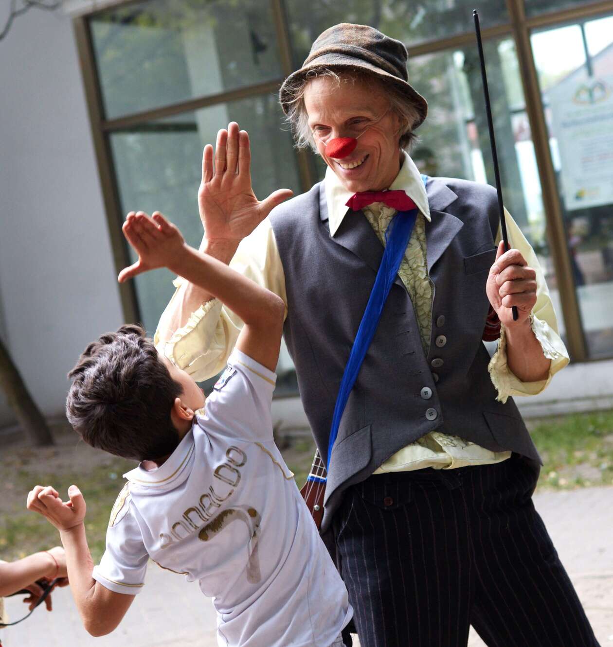 Der Clown Filou gibt einem Jungen in einem Flüchtlingheim einen Handschlag 