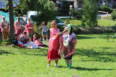 Zwei Clowns die draußen auf einer Wiese stehen und im hintergrund sieht man noch andere Workshop Teilnehmer 