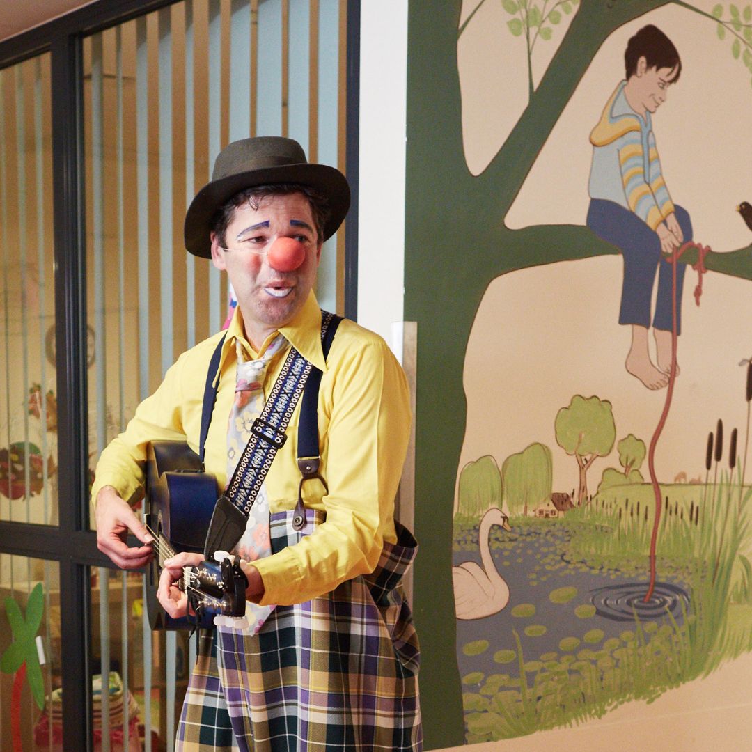 Clown Leofino spielt im Krankenhausflur auf seiner Ukulele.